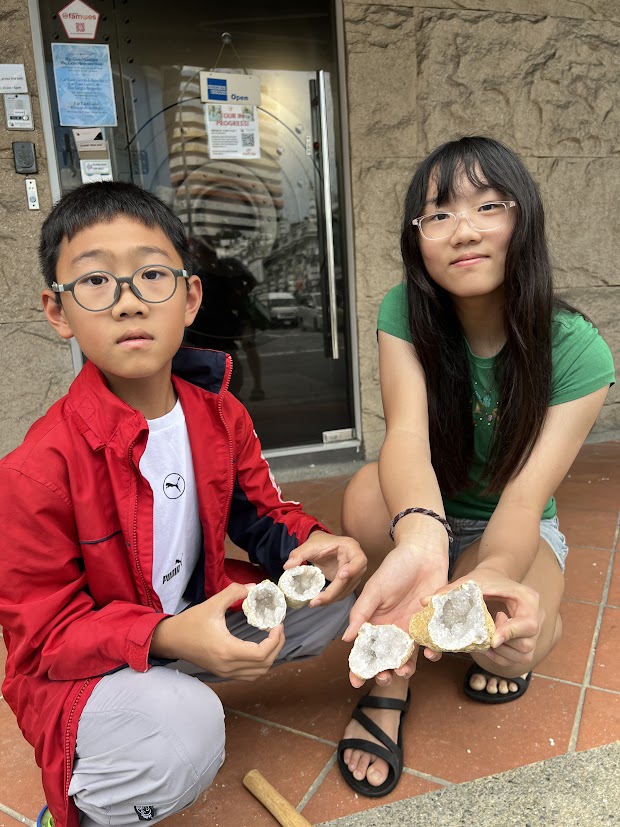 Two children holding their cracked geodes outside The Gem Museum Singapore