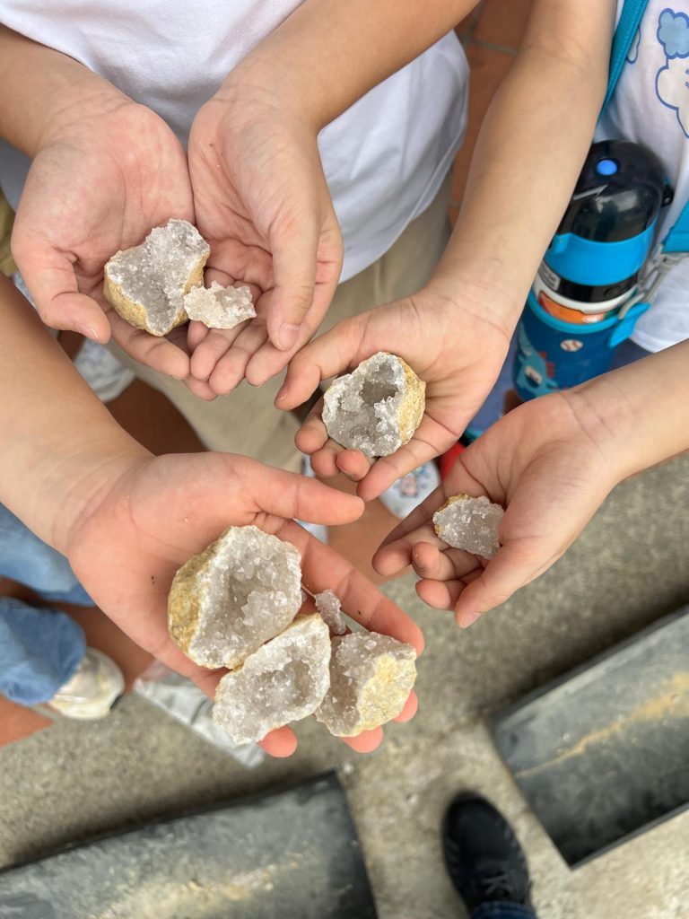 Gems for Children : Children's hands holding the two halves of a cracked geode at The Gem Museum Singapore