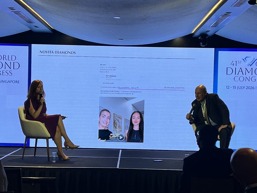 Two panelists seated on stage discussing misleading advertising practices, with a screen behind them displaying a flagged Novita Diamonds Instagram giveaway post.